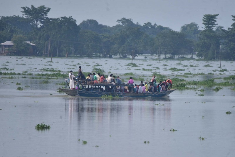 Morigaon: Villagers row their boat through the floodwaters as they move to take shelter at a highland after heavy rains left the Sildubi village submerged under water in the flood-hit Morigaon district of Assam on June 29, 2020. (Photo: IANS)