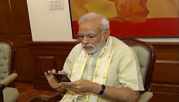 Prime Minister Narendra Modi busy working on his mobile phone. (Photo: IANS)